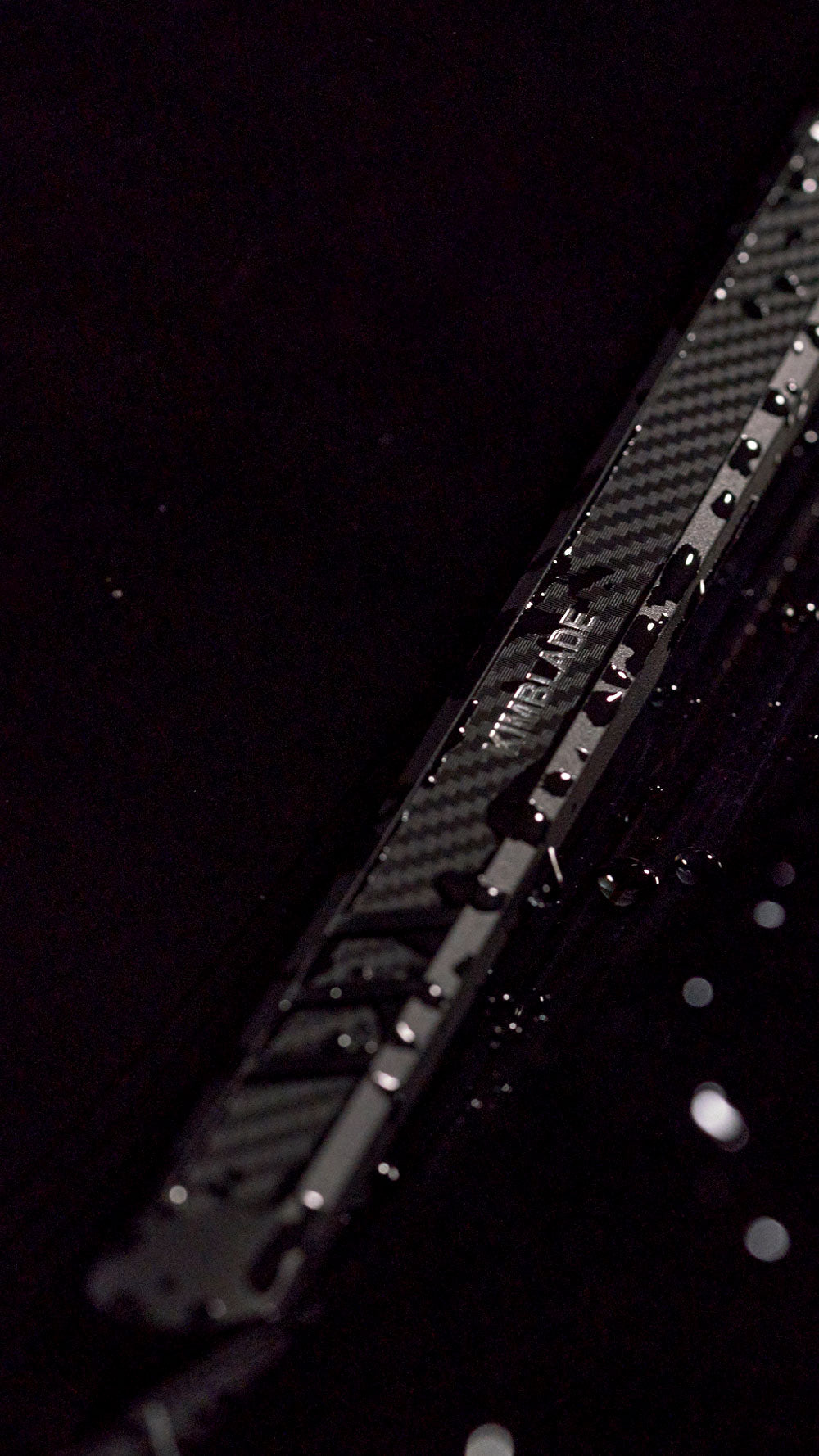 Close-up of Kimblade CarbonFit wiper with sleek carbon fiber pattern and water droplets highlighting its water-repellent surface and stylish durability